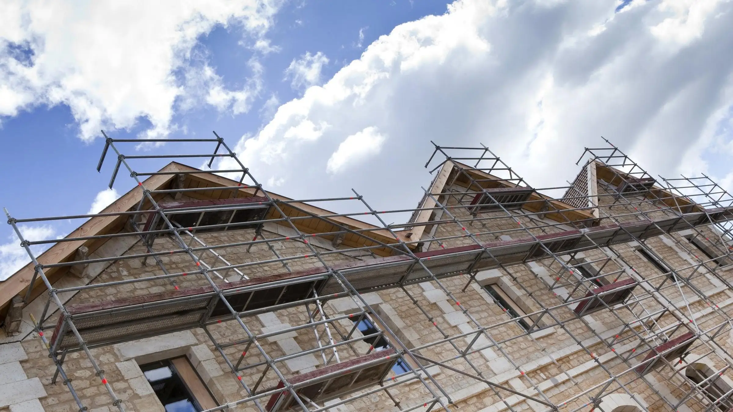 Façade en pierre calcaire sous échafaudage, toiture en cours de réfection